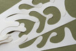 abstractly cut blank paper with elegant shapes arranged on rough green paper
