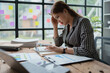 © Jirapong - female employee holds a pen and checks investment financial documents.
