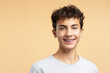 © Maria Vitkovska - Portrait of smiling handsome boy with braces looking at camera posing isolated on beige background