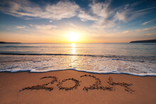 Happy New Year 2024 Concept, Lettering On The Beach. Written Text On The Sea Beach At Sunrise.
