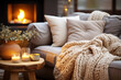 Beige chunky knit throw on grey sofa. Сoffee table with candles against fireplace. Scandinavian farmhouse, hygge home interior design of modern living room. Warm and inviting winter atmosphere.