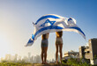 Two girls waving the Israel flag as an Iron Dome. They look at the horizon of Givatayim. Yom Haatzmaut or Stand with Israel concept