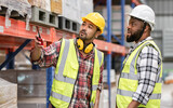 Fototapeta  - Asian, African diverse professional male workers inspecting, checking shipping stocks in storage, warehouse or factory for delivery, wearing safety hat. Commercial Industry Business Concept.