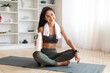 © Prostock-studio - Sporty lady sitting on sports mat with bottle of water
