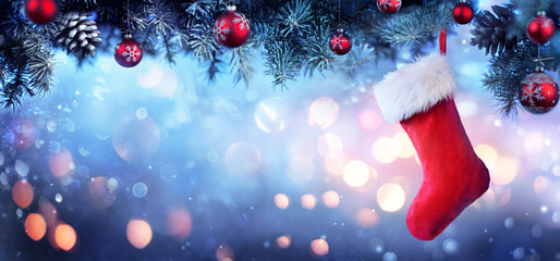 Wall Mural - stocking hanging christmas tree - red sock with snow and bokeh lights