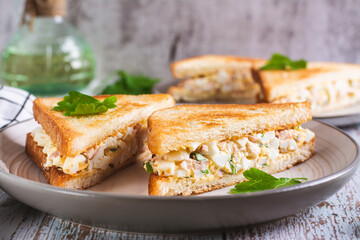 Wall Mural - Chopped sandwiches with egg, bacon and herbs salad on a plate on the table