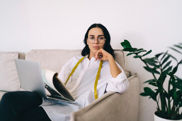 Canvas Print - Female designer with computer and sketchbook sitting on comfortable couch