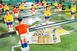 Table football game with euro bills scattered around plastic players, concept of manipulated paid matches