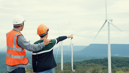 Wall Mural - Engineer with his son on a wind farm atop a hill or mountain in the rural. Progressive ideal for the future production of renewable, sustainable energy. Energy generation from wind turbine.