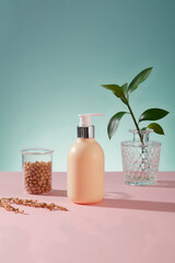 Wall Mural - Unlabeled pump bottle in yellow color decorated with a beaker of soybeans against blue background. Cosmetic product advertising with empty label