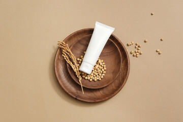 Wall Mural - A tube without label placed on wooden dishes with soybeans. Soybean (Glycine max) benefits include brightening your skin and reducing redness