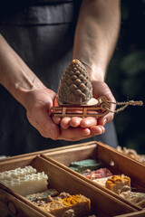 A woman soap maker holds soap in her hands in the form of colorful coniferous cones. An interesting gift for New Year's holidays and Christmas. Eco-friendly natural handmade cosmetics