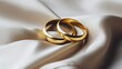 a pair of gold rings on a white fabric
