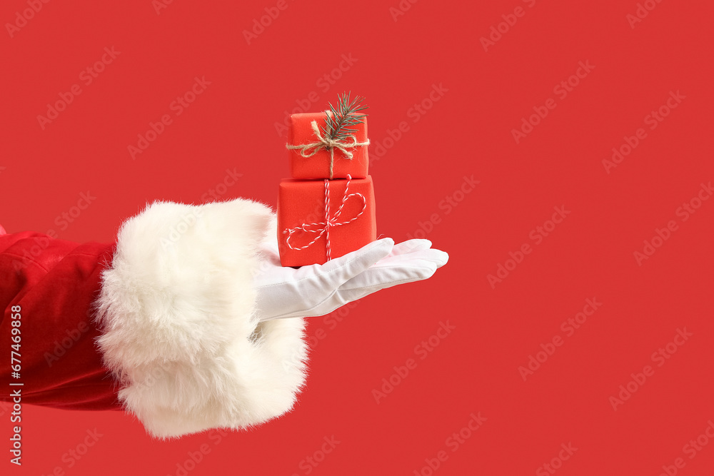 Santa Claus with red gift boxes and Christmas tree branch on color background