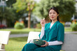 © DragonImages - Portrait of cheerful medical nurse eating fresh fruits when resting on bench in park during her break