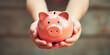 Kid hand holding pink piggy bank, saving money or finance concept
