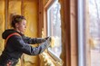 © Marcos - Empowered Craftswoman: Female Construction Worker Ensures Thermal Comfort with Glass Wool in Wooden Home