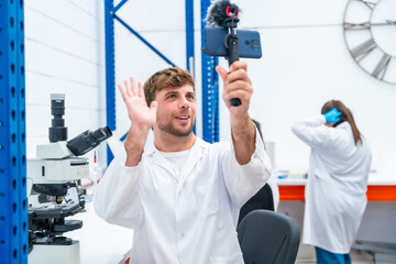 Wall Mural - scientist waving while broadcasting using phone in a research laboratory