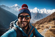 Ein junger hübscher Mann macht ein Selfie von sich. Er trägt Outdoorkleidung eine Kopfbedeckung und eine Sonnenbrille. Im Hintergrund sind schneebedeckte Berge und Gletscher.