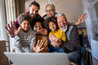 © NDABCREATIVITY - Extended multiethnic family together at home during video call. People happiness technology concept