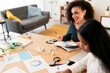 © Studio Marmellata - High angle of young female office workers in casual clothes sitting at wooden table with charts and laptop while working on project in modern workspace at daylight