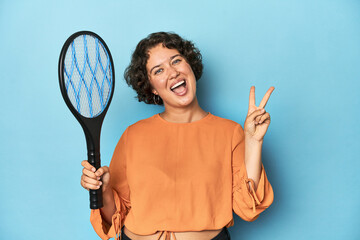 Young woman with electric mosquito racket Young woman with electric mosquito racketjoyful and carefree showing a peace symbol with fingers.