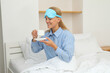 © Atlas - Young woman in sleeping mask drinking coffee in bed