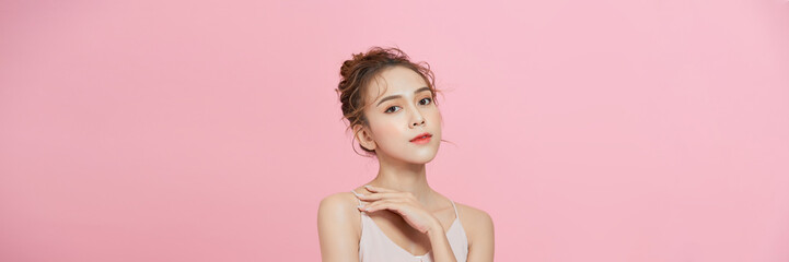 Wall Mural - beauty Asian woman with K-beauty makeup showing fresh and clean skin isolated on pink background