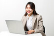 © Bojan - Attractive Asian business woman working on laptop while sitting at desk. Happy Chinese woman isolated on light grey background