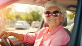 Fototapeta Londyn - Joyful mature woman wearing sunglasses driving a car and looking at camera through open window. Happy senior woman driver, active aging concept, retirement activity. Road trip. Driving courses