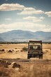 The rear perspective of a parked safari jeep in a dusty landscape with mountains under a clear sky