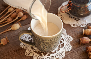 Wall Mural - Homemade vegan poppy seed milk being poured from a jug into a cup