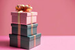 Três caixas de presente empilhadas com fundo cor-de-rosa.