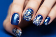 Christmas manicure on women's hands with blue and white colors and with holiday design