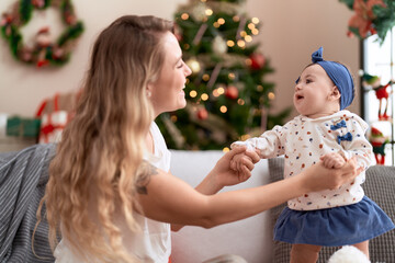 Canvas Print - Woman and toddler standing on sofa by christmas tree at home