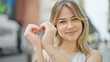 © Krakenimages.com - Young blonde woman smiling confident doing heart gesture with hands at street