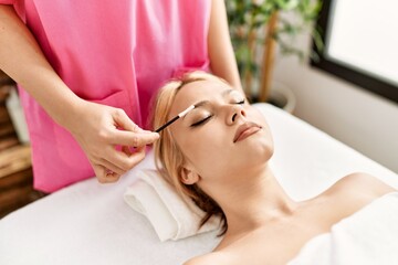 Poster - Young caucasian woman lying on table having eyelashes treatment at beauty salon