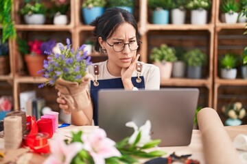 Canvas Print - Young hispanic woman working at florist shop doing video call touching mouth with hand with painful expression because of toothache or dental illness on teeth. dentist concept.