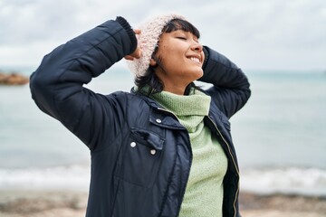 Sticker - Young beautiful hispanic woman smiling confident relaxed with hands on head at seaside