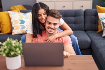 Wall Mural - Man and woman couple using laptop sitting on sofa at home