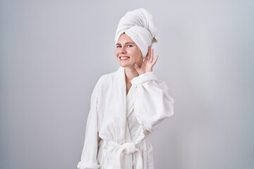 Poster - Blonde caucasian woman wearing bathrobe smiling with hand over ear listening an hearing to rumor or gossip. deafness concept.