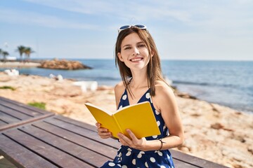 Sticker - Young blonde woman tourist reading book sitting on bench at seaside