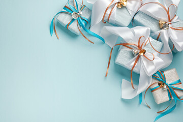 Wall Mural - Gift boxes wrapped in blue, white and silver paper with white, blue and gold ribbon bows. Blue background, top view. Christmas and New Year gifts, Boxing Day.