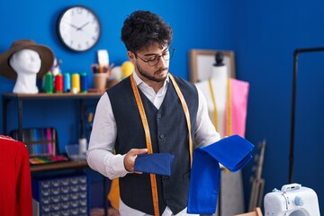 Canvas Print - Young hispanic man tailor holding cloths at sewing studio