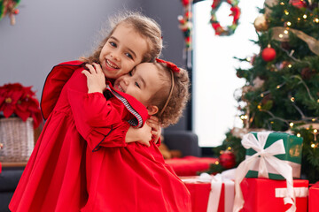 Canvas Print - Adorable girls hugging each other celebrating christmas at home