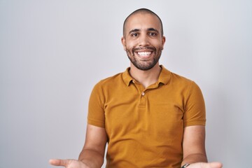 Canvas Print - Hispanic man with beard standing over white background smiling cheerful with open arms as friendly welcome, positive and confident greetings