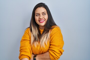 Canvas Print - Young hispanic woman standing over isolated background looking away to side with smile on face, natural expression. laughing confident.