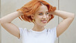 © Krakenimages.com - Young redhead woman smiling confident looking to the side combing hair with hands at street