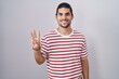 © Krakenimages.com - Hispanic man with long hair standing over isolated background showing and pointing up with fingers number three while smiling confident and happy.
