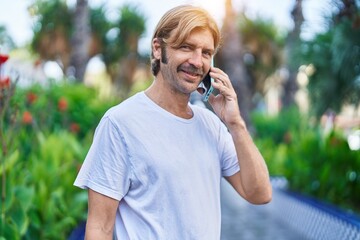 Sticker - Young blond man smiling confident talking on the smartphone at park